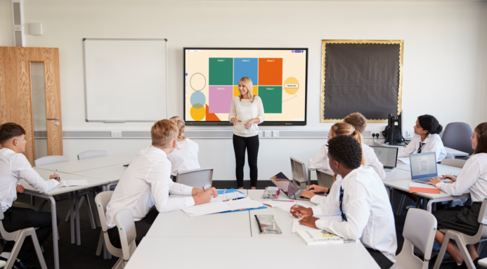 A teacher stands at the front of a classroom of high school students, explaining how to create and use plot diagrams.