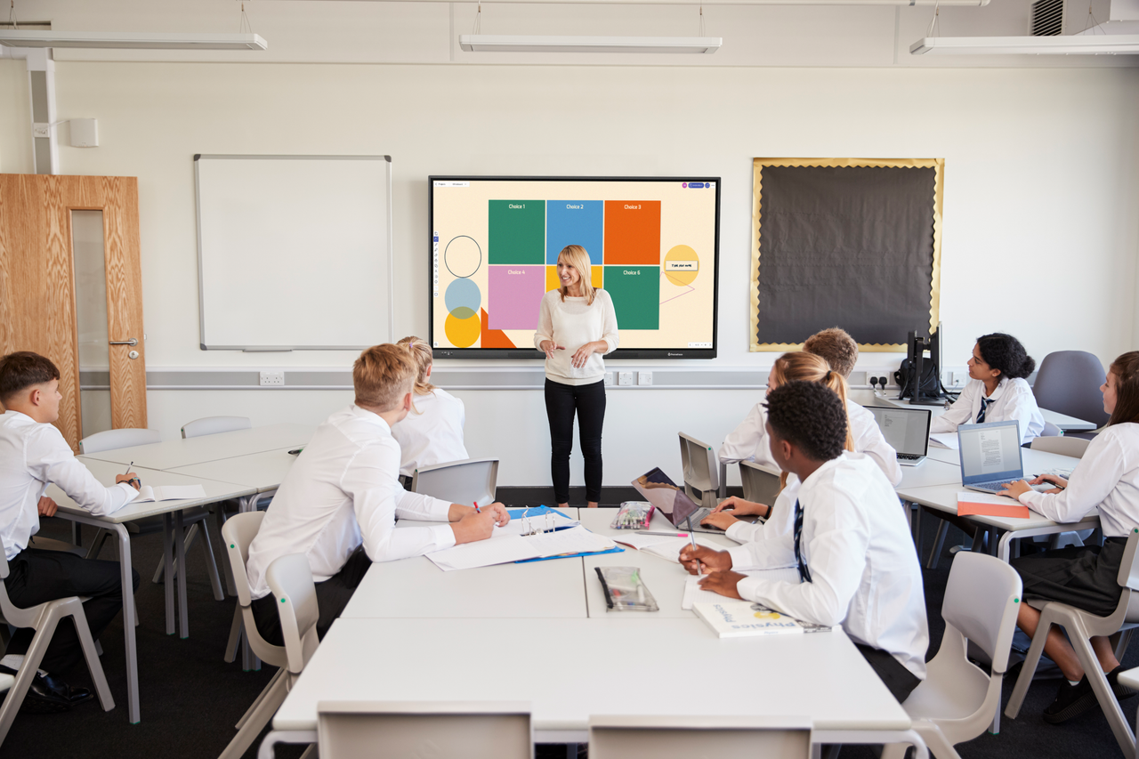 A teacher stands at the front of a classroom of high school students, explaining how to create and use plot diagrams.